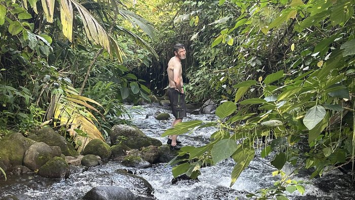 Sig standing in a forest creek.
