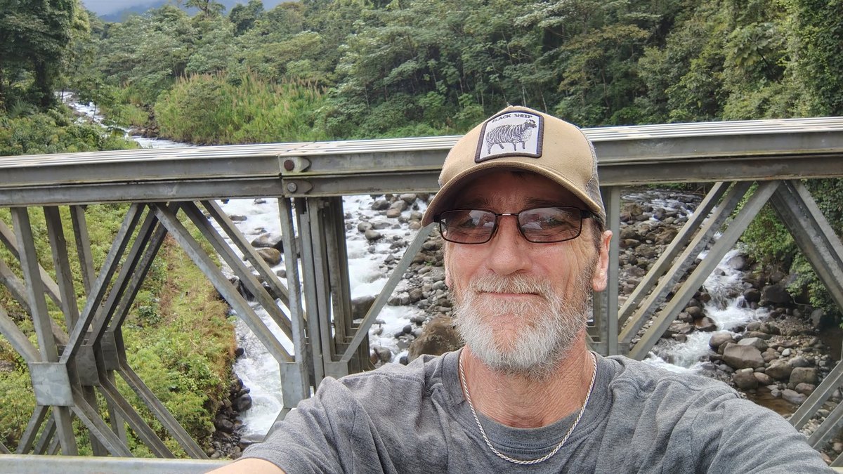 Sig taking a selfie on a bridge above a river.
